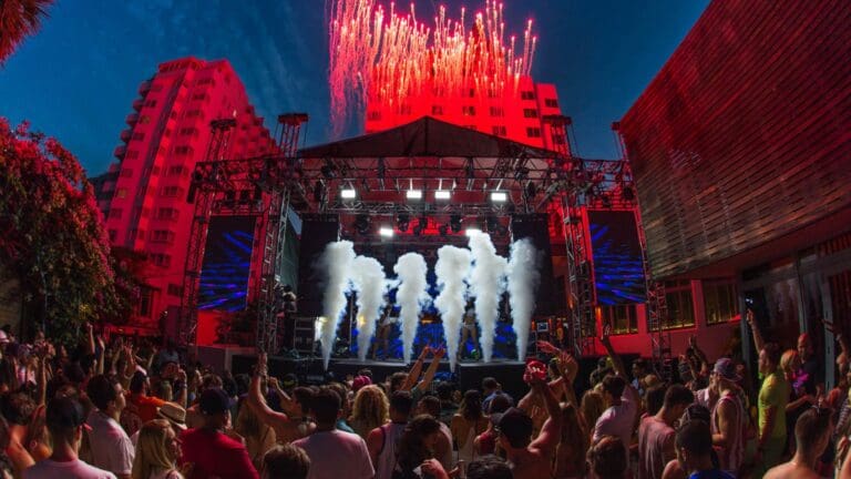 Escenario iluminado en un evento cultural urbano con público disfrutando en un espacio abierto