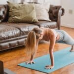 Mujer haciendo ejercicio en casa con esterilla, representando un estilo de vida saludable para perder peso de forma natural.