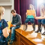 Grupo de adultos en Valencia participando en un curso de teatro, practicando una escena sobre el escenario como parte de una clase de actuación.