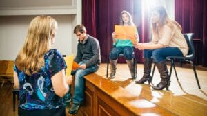 Grupo de adultos en Valencia participando en un curso de teatro, practicando una escena sobre el escenario como parte de una clase de actuación.