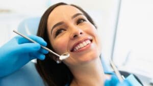Paciente sonriente en clínica dental después de tratamiento completo con ortodoncia, implantes y estética dental.