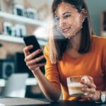 Persona siendo identificada mediante biometría facial en una pantalla digital con escaneo de documentos en segundo plano