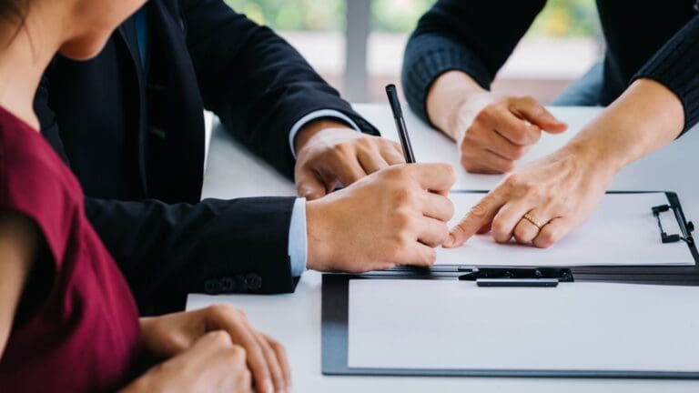 Pareja firmando un acuerdo de divorcio junto a un abogado, simbolizando el proceso de divorcio express y la asesoría legal especializada