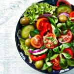 Ensalada gourmet con ingredientes frescos, cereales y vegetales de colores en vista cenital, lista para llevar.
