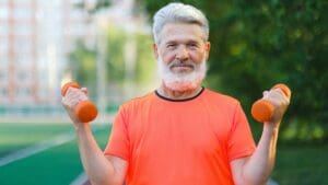 Hombre mayor ejercitándose al aire libre con pesas pequeñas como parte de una rutina integral para mantener la salud física y mental