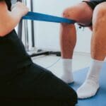 Fisioterapeuta aplicando tratamiento manual para recuperación de lesión muscular en paciente deportista