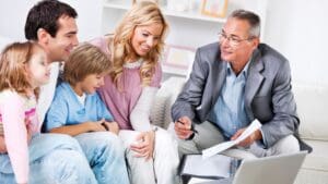 Familia española sonriente recibe asesoramiento sobre seguros de salud y vida con tranquilidad y confianza en una correduría profesional
