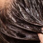 Mujer con cabello brillante en tratamiento de hidratación capilar con productos naturales en spa