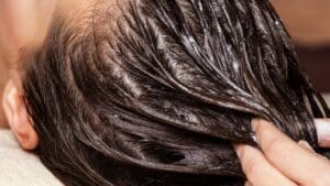 Mujer con cabello brillante en tratamiento de hidratación capilar con productos naturales en spa
