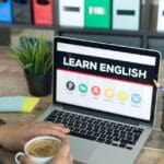 Estudiante en clase online de inglés con profesor, aprendiendo desde casa con materiales interactivos para avanzar en su nivel del idioma