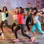Adultos aprendiendo a bailar en grupo dentro de una academia, expresando felicidad y bienestar en un entorno relajado y profesional
