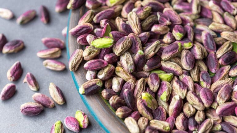 Pistachos crudos ecológicos en cuenco de madera sobre fondo claro como snack saludable y natural para una dieta equilibrada