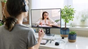 Mujer joven en sesión de terapia psicológica online desde casa, conectando por videollamada en un entorno tranquilo y acogedor