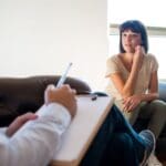 Sesión de terapia psicológica entre adulto y psicóloga en un entorno profesional y acogedor