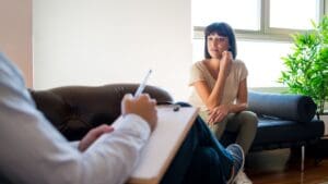 Sesión de terapia psicológica entre adulto y psicóloga en un entorno profesional y acogedor