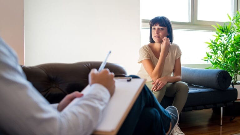 Sesión de terapia psicológica entre adulto y psicóloga en un entorno profesional y acogedor