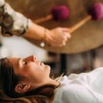 Mujer recibiendo una sesión de terapia de sonido con gong en un espacio de meditación, rodeada de energía vibracional y atmósfera de sanación emocional.