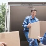 Trabajadores profesionales de mudanzas organizando cajas con cuidado y seguridad