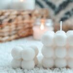 Velas artesanales decorativas y personalizadas sobre mesa rústica, con frascos de vidrio, flores secas y luz cálida, ideales para eventos y regalos únicos.