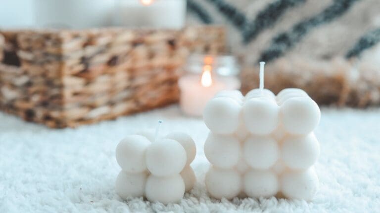 Velas artesanales decorativas y personalizadas sobre mesa rústica, con frascos de vidrio, flores secas y luz cálida, ideales para eventos y regalos únicos.