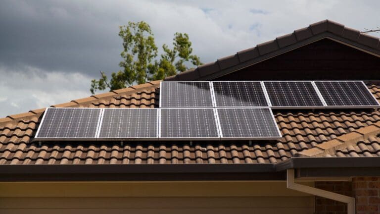 Vista de una casa moderna equipada con paneles solares y entorno natural que refleja sostenibilidad y eficiencia energética