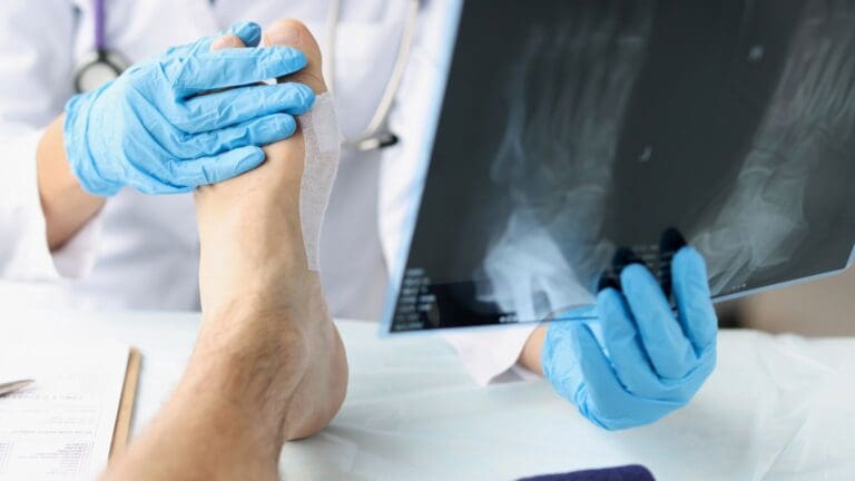 Traumatólogo en consulta médica evaluando el pie de un paciente con dolor o lesión en clínica especializada