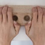 Escalador entrenando con fingerboard portátil en casa para mejorar fuerza de dedos