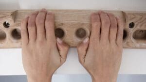 Escalador entrenando con fingerboard portátil en casa para mejorar fuerza de dedos