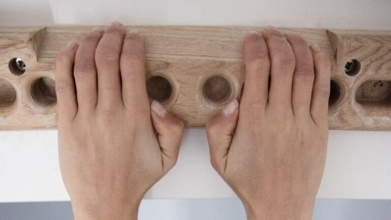 Escalador entrenando con fingerboard portátil en casa para mejorar fuerza de dedos