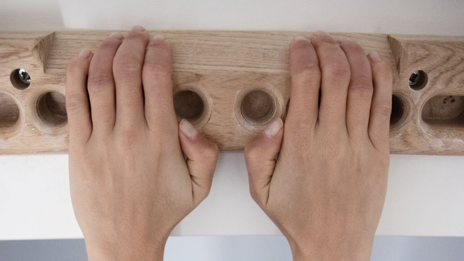Escalador entrenando con fingerboard portátil en casa para mejorar fuerza de dedos