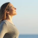 Mujer en un entorno tranquilo, meditando al aire libre, simbolizando la recuperación emocional y el equilibrio mental tras una crisis emocional.
