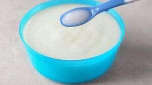 Papilla blanca natural en un cuenco azul con cucharita infantil, lista para alimentar a un bebé