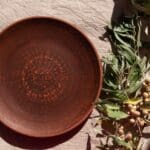Delantal de lino hecho a mano, accesorios de cerámica y artesanía catalana sostenible sobre una mesa de madera