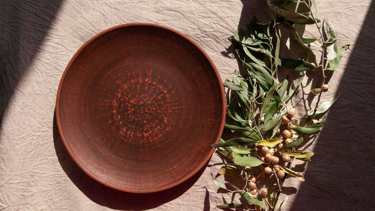 Delantal de lino hecho a mano, accesorios de cerámica y artesanía catalana sostenible sobre una mesa de madera