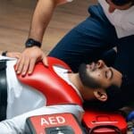 Persona utilizando desfibrilador automático DEA en una emergencia de paro cardíaco.
