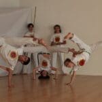 Personas practicando capoeira en grupo con actitud relajada y expresiva