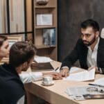 Profesional legal ofreciendo asesoría jurídica personalizada a un cliente en una oficina moderna.