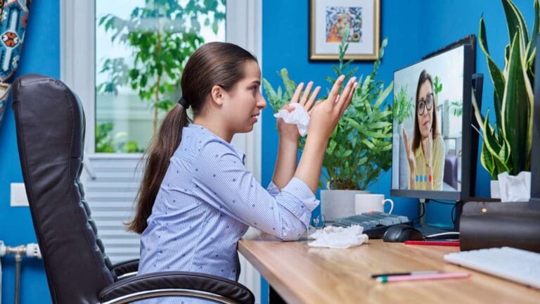 Mujer adulta en videollamada desde casa durante una sesión de terapia online, con expresión tranquila y entorno acogedor.