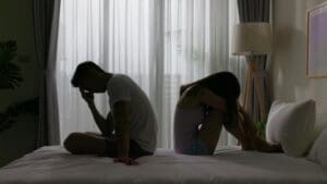 Pareja sentada en la cama enfrentando una ruptura emocional en silencio y tensión