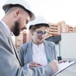 Ingenieros revisando planos técnicos en un local, gestionando documentación para obtener una licencia de actividad en Barcelona o Cataluña.
