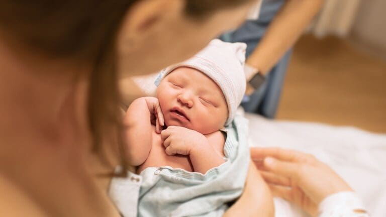 Madre primeriza con su bebé en brazos en casa usando ropa cómoda de maternidad