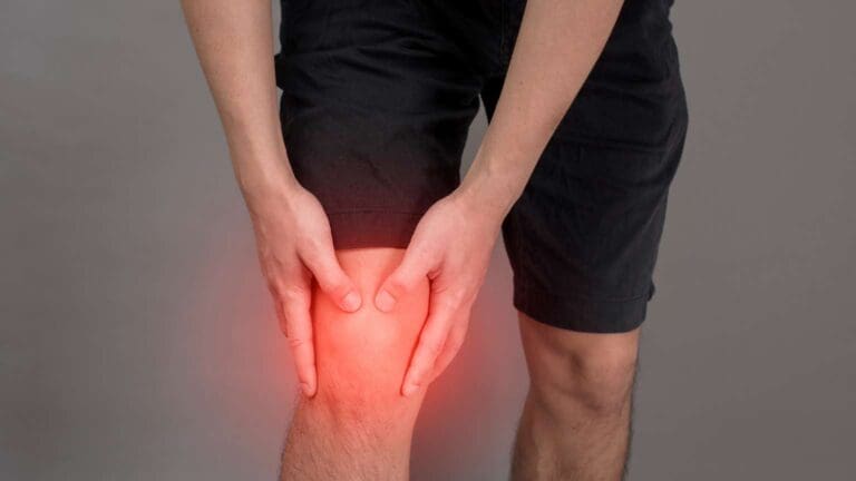 Persona con dolor crónico en la rodilla sujetándola con las manos. Representación de molestias físicas tratadas mediante pedagogía del dolor.