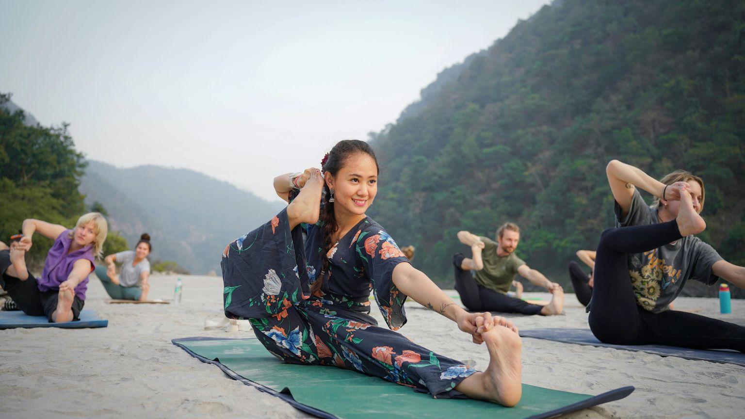 Personas practicando distintos tipos de yoga al aire libre en grupo, representando niveles y energías diferentes en un entorno natural y espiritual.