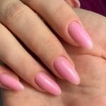 Mano con uñas de acabado gel en tono rosa natural, ejemplo visual para comparar con uñas acrílicas en términos de brillo, forma y estilo.