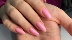 Mano con uñas de acabado gel en tono rosa natural, ejemplo visual para comparar con uñas acrílicas en términos de brillo, forma y estilo.
