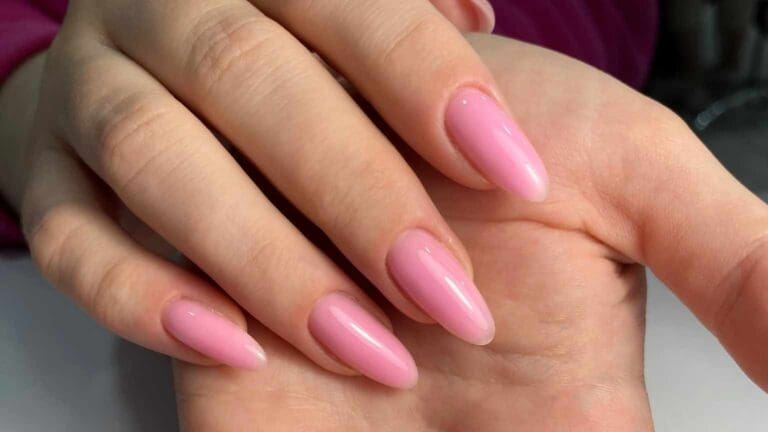 Mano con uñas de acabado gel en tono rosa natural, ejemplo visual para comparar con uñas acrílicas en términos de brillo, forma y estilo.