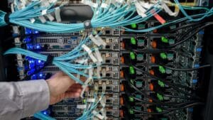Técnico revisando cableado estructurado en servidor. Mantenimiento informático en centros de datos para garantizar conectividad y rendimiento continuo.