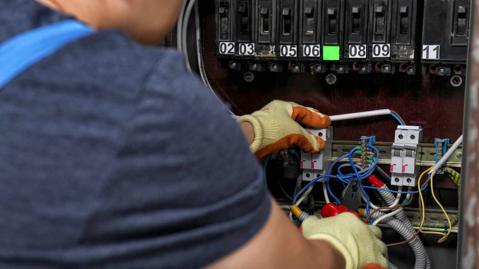 Electricista trabajando en cuadro eléctrico moderno, realizando ajustes y conexiones seguras, representando la importancia de una instalación eléctrica profesional en espacios con alta demanda tecnológica.