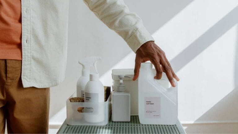 Productos de limpieza sin fosfatos sobre una mesa junto a una persona simbolizando sostenibilidad, cuidado de la piel y del hogar.