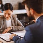 Mujer joven firmando su primer contrato laboral con asesoramiento profesional en derecho laboral